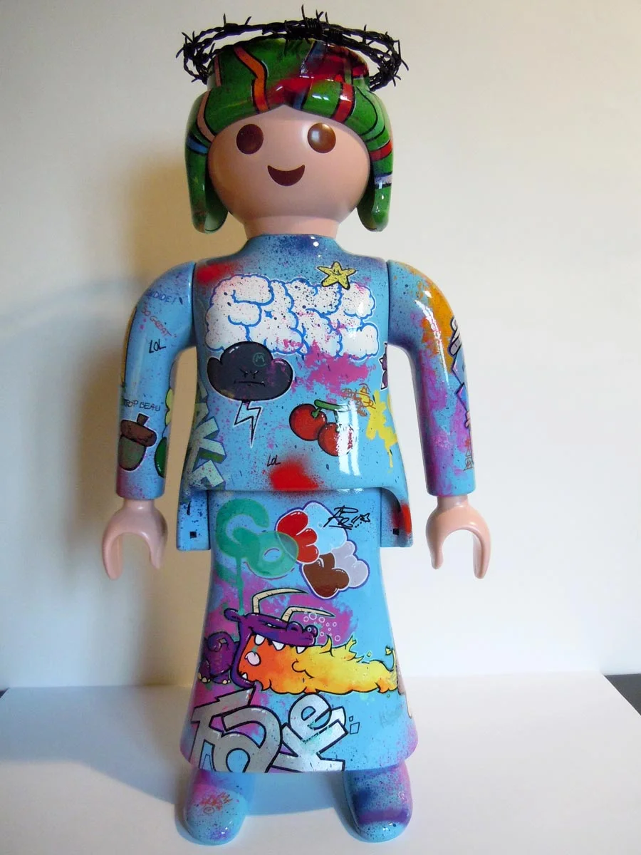 Playmobil bleu ciel, graffé avec une couronne en fil de fer barbelé