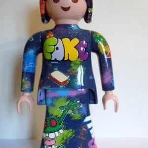 Playmobil bleu foncé et violet, graffé avec un coeur en puzzle dans le dos et une couronne en barbelé