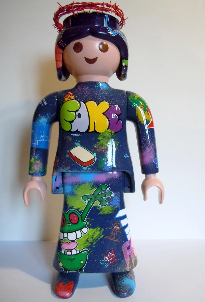 Playmobil bleu foncé et violet, graffé avec un coeur en puzzle dans le dos et une couronne en barbelé