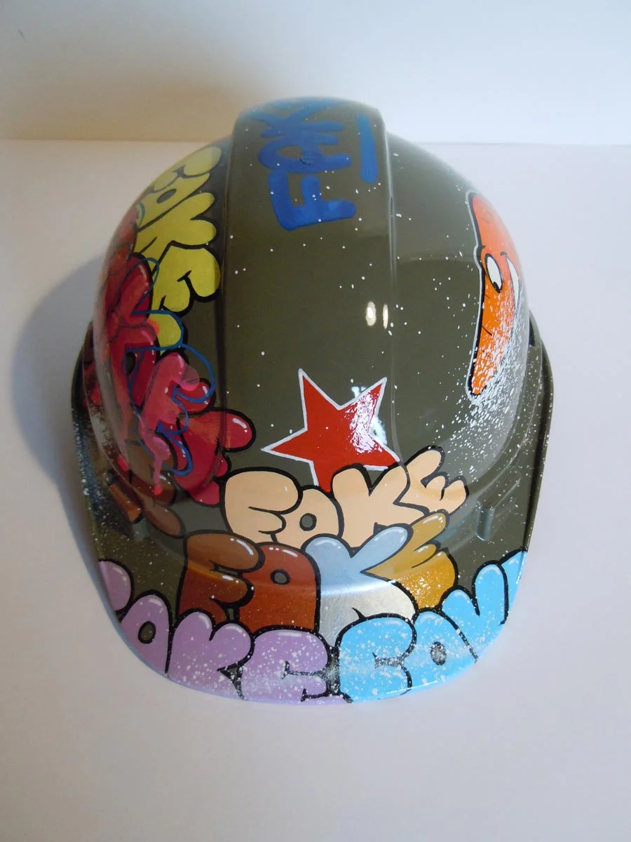 Casque vert armée, graffé avec accumulation de tag Fake de différentes couleurs