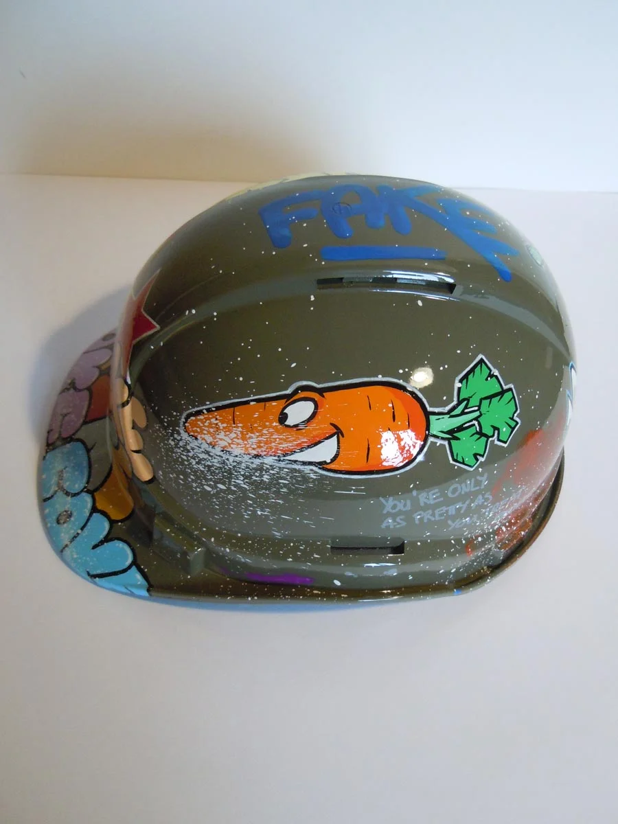 Casque vert armée, graffé avec accumulation de tag Fake de différentes couleurs