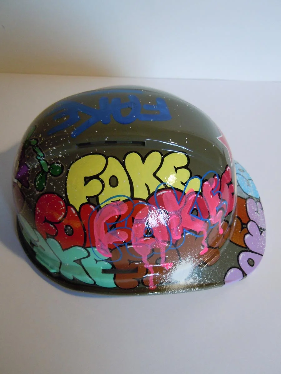 Casque vert armée, graffé avec accumulation de tag Fake de différentes couleurs