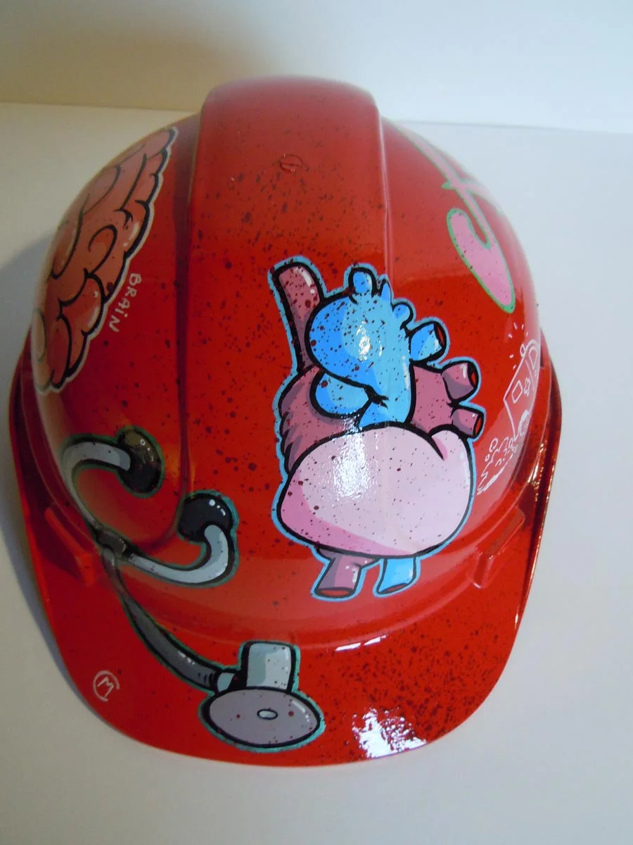 Casque rouge vif, graffé, avec des organes peints dessus (coeur, cerveau etc...).