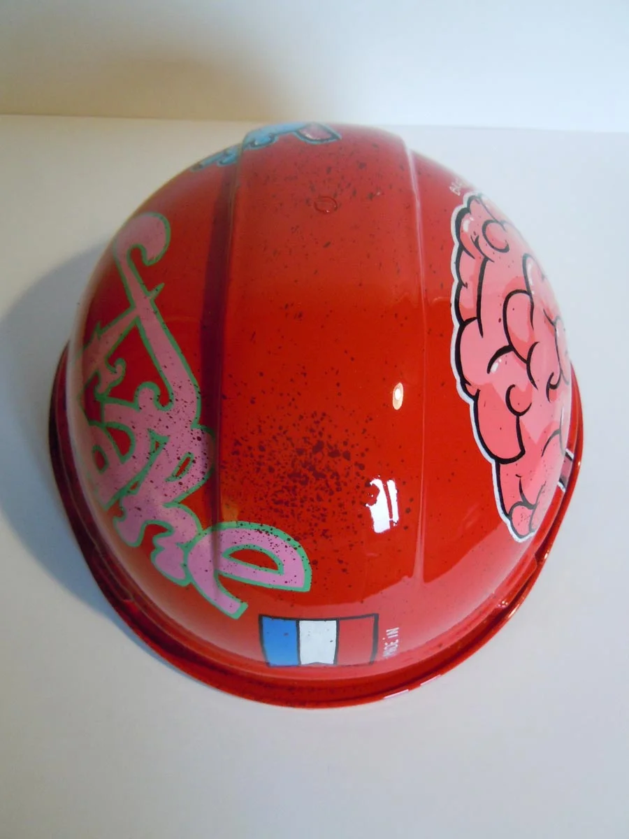 Casque rouge vif, graffé, avec des organes peints dessus (coeur, cerveau etc...).