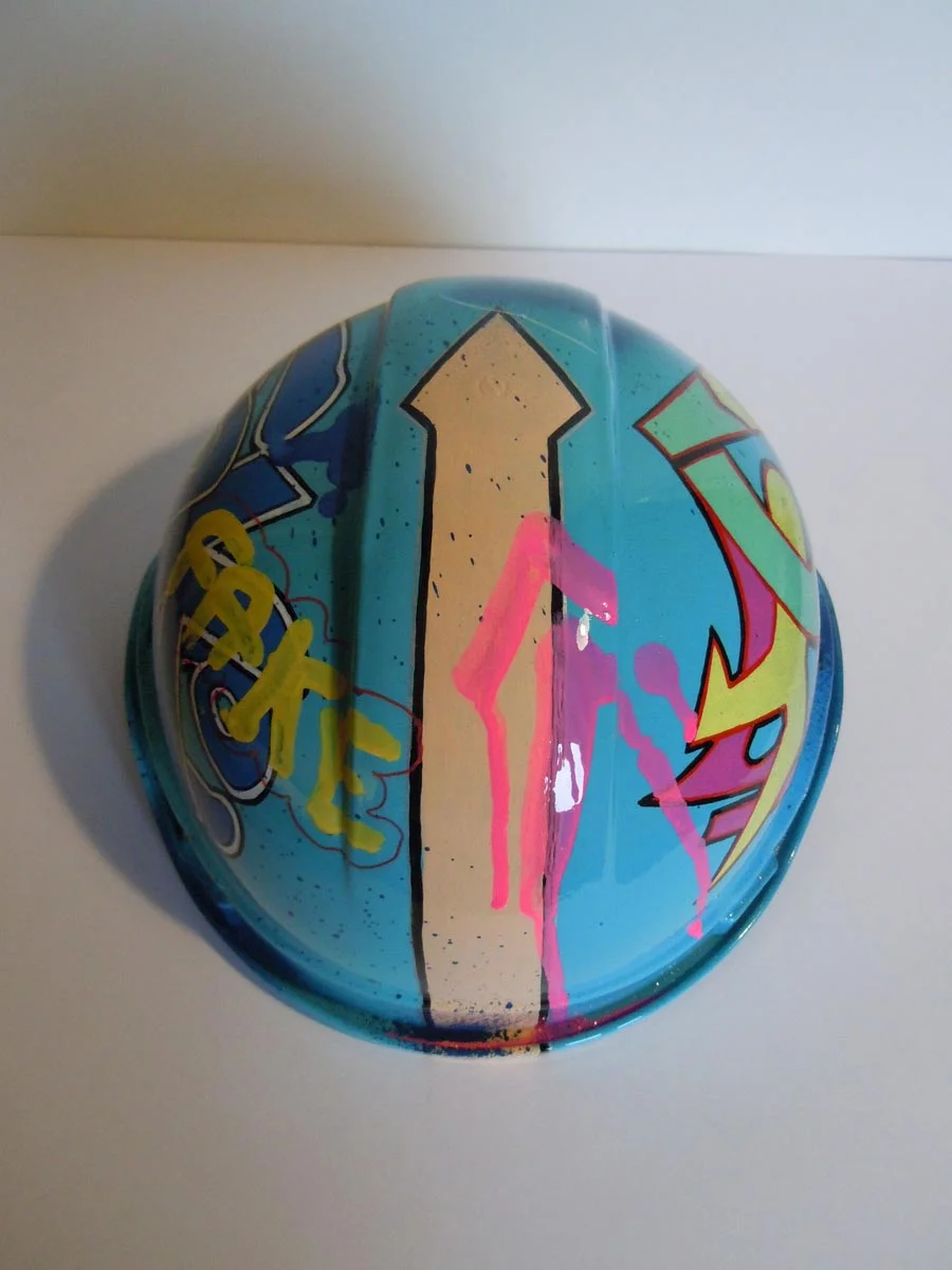 Casque bleu clair, graffé, avec un personnage manga sur le devant.