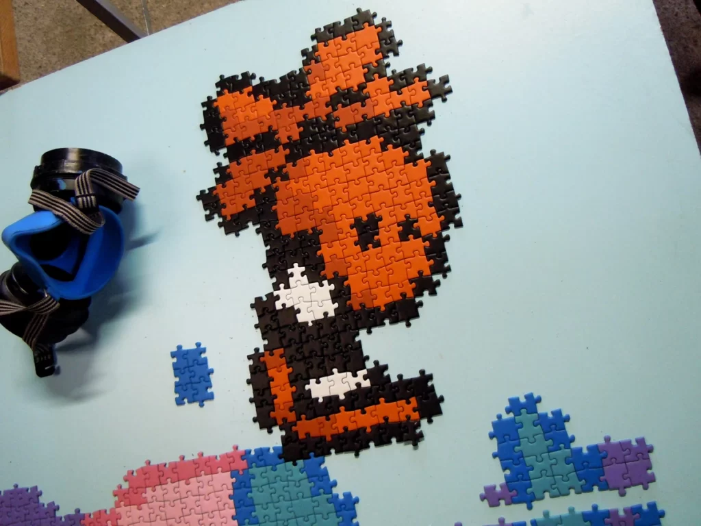 Photo d'une martie du puzzle géant en cours de réalisation. On voit un petit personnage orange avec une hélice sur la tête.