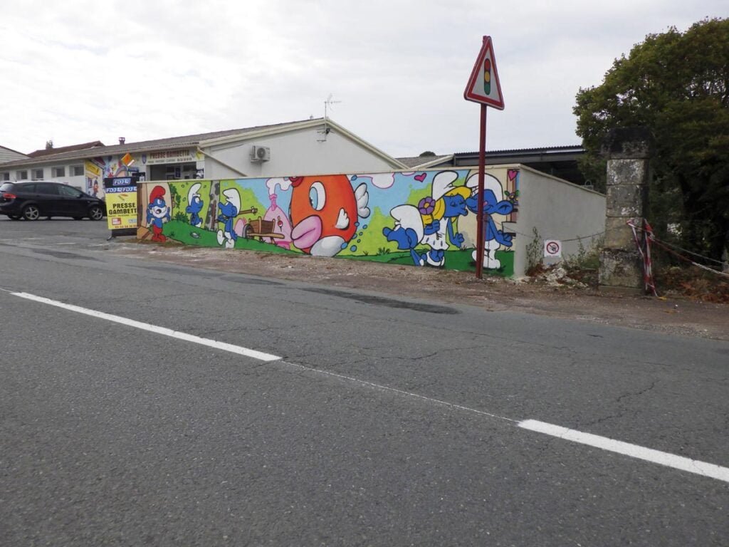 Photo de 3/4 de la fresque dans sa globalité. On y voit au fond le grand Schtroumpf étonné de la prise d'un de ses Schtroumpf à la pêche et sur la côté droit, on y voit la Schtroumpfette qui fait un bisou à un autre Schtroumpf qui vient de lui offrir une fleur.