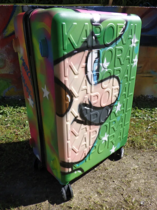Photo de la valise rigide à roulette. Sur cette photo on voit la coté avec Luigi de graffé dessus. On voit Luigi de profil. Une belle façon de voyager avec style.