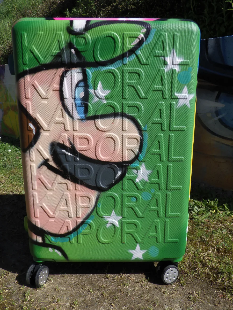 Photo du coté de la valise à roulette graffé aux couleurs de mario bros et Luigi. Sur cette photo on voit la coté avec la tête de Luigi. Une belle façon de voyager avec style.
