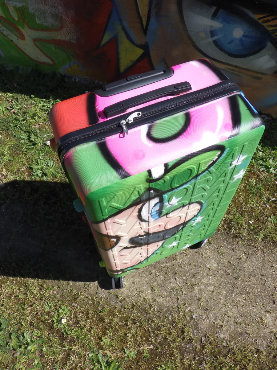Vue de dessus de la valise graffé aux couleurs de Mario et Luigi. On distingue très bien que cette valise est parfaitement fonctionnelle malgré le fait que ce soit une oeuvre d'art unique. Une belle façon de voyager avec style.
