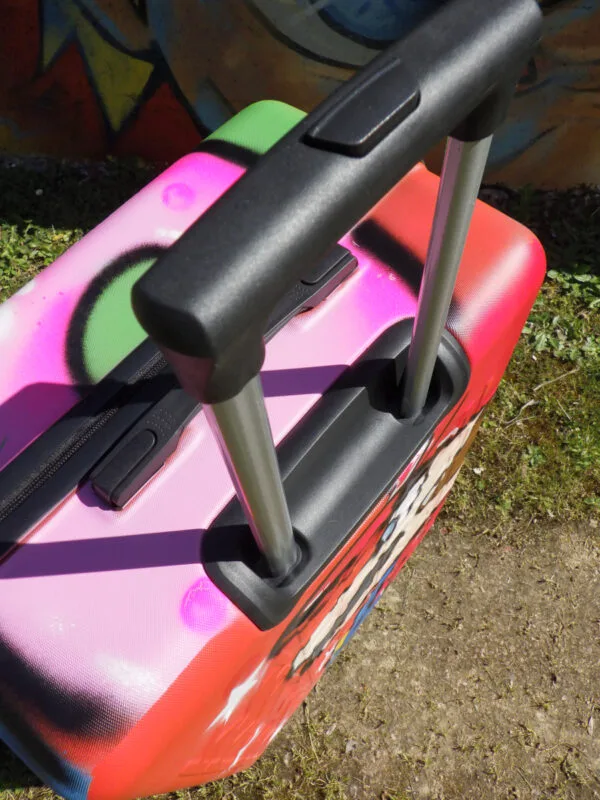 Gros plan sur la poignée de la valise qui est dépliée. Cette valise qui est une véritable pièce de collection est malgré tout, tout à faire utilisable dans la vie de tous les jours. Une belle façon de voyager avec style.