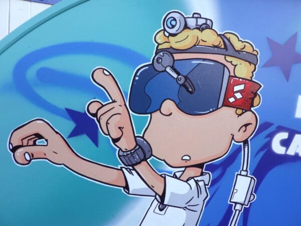 Gros plan sur le casque de réalité virtuelle que porte le personnage principal de la peinture. On voit que c'est un casque fait maison. Il est fait de bric et de broc. On dirait un masque de ski auquel on a ajouté des essuis glace et une lampe torche, le tout relié à une batterie de voiture pour l'alimentation électrique.