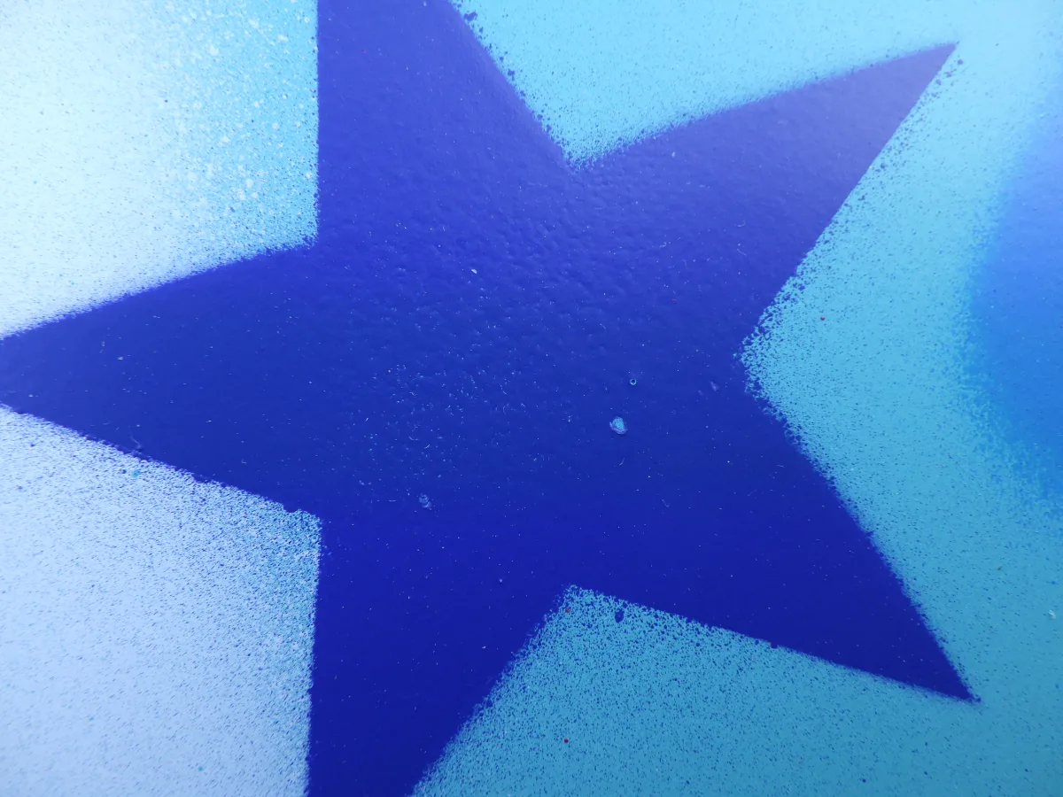 Gros plan sur un élément du fond de la peinture. il s'agit d'une étoile faite au pochoir. Elle est bleu foncé sur des nuances de bleus plus clairs. Ce type d'étoiles revient souvent dans les créations de Marcel Champion. Certainement un clin d'oeil à sa passion pour l'astronomie.