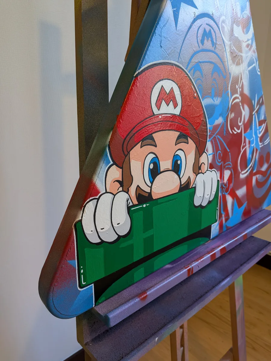 Vue de coté du panneau Mario. Cet angle de vue permet de voir qu'il s'agit d'un panneau recyclé. On distingue encore les affres du temps sur la support. Cela permet également de voir que la peinture n'est pas vernie.