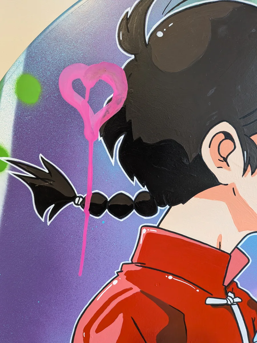 Cette image est un gros plan d’une peinture réalisée sur un véritable panneau de signalisation routière. On y voit en détail le personnage masculin (Ranma Saotome en tenue rouge chinoise avec sa célèbre tresse noire) en train d’embrasser tendrement Akane. L’élément qui attire immédiatement l’œil est le grand cœur rose fluo rose bonbon, peint à la bombe avec un effet dripping prononcé : il semble littéralement couler le long de la tresse de Ranma, comme si l’amour débordait. Ce cœur tagué, volontairement brut et street-art, contraste avec la finesse du dessin anime et transforme ce vieux panneau métallique en une déclaration romantique et urbaine ultra-pop. Une touche graffiti pleine d’humour et de tendresse sur un support détourné !