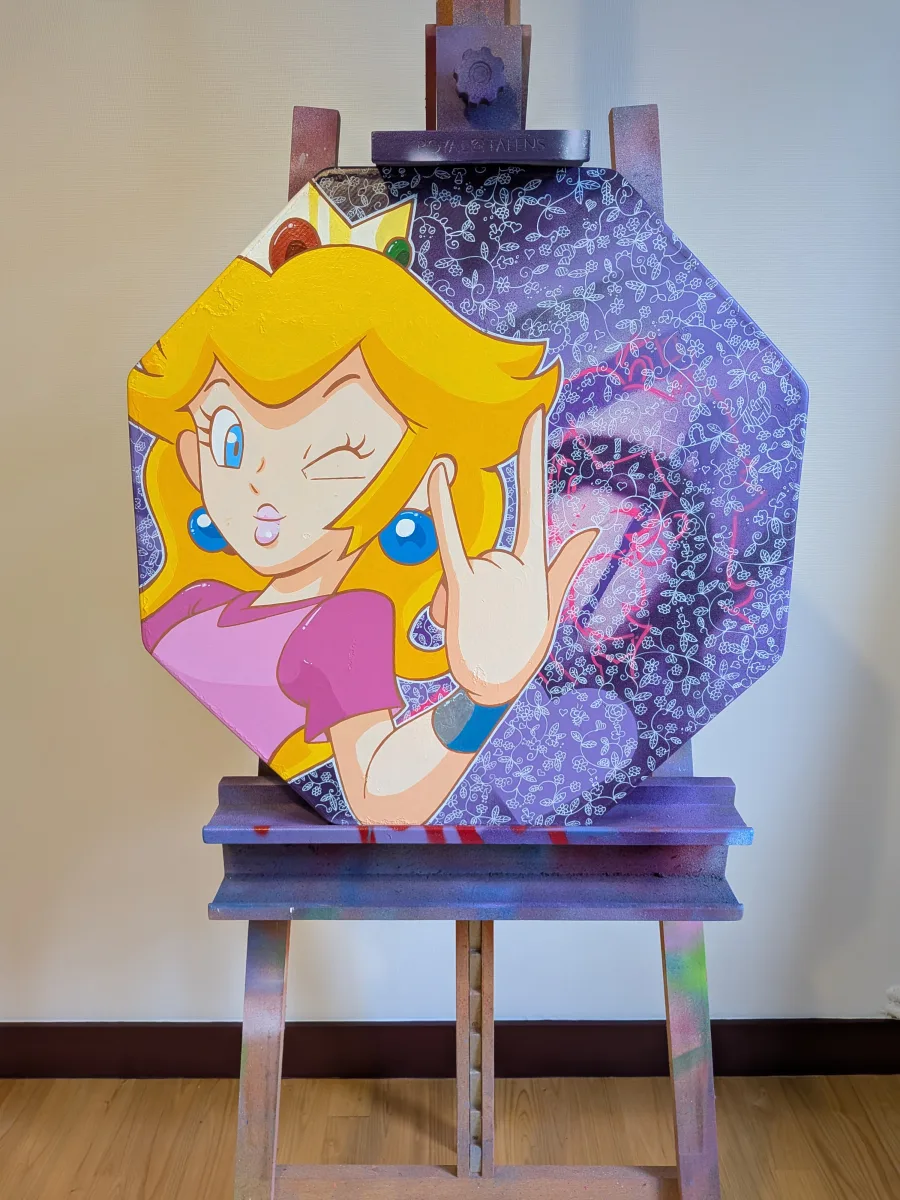 Cette image présente une peinture originale réalisée sur un authentique panneau de signalisation routière métallique à huit côtés (format « stop » recyclé).Princesse Peach (Super Mario) y apparaît en version ultra-pop et rebelle : clin d’œil malicieux, langue tirée et signe « rock » avec la main, vêtue de sa robe rose iconique. Le fond violet profond est couvert de motifs floraux blancs délicats, contrastant avec l’attitude espiègle du personnage et quelques touches de spray rose fluo qui débordent.Le support conserve sa forme et son éclat d’origine, transformant un simple panneau de rue en une œuvre pop-art joyeuse et pleine d’humour. Une pièce unique qui détourne avec audace l’univers Nintendo en décoration murale vitaminée !