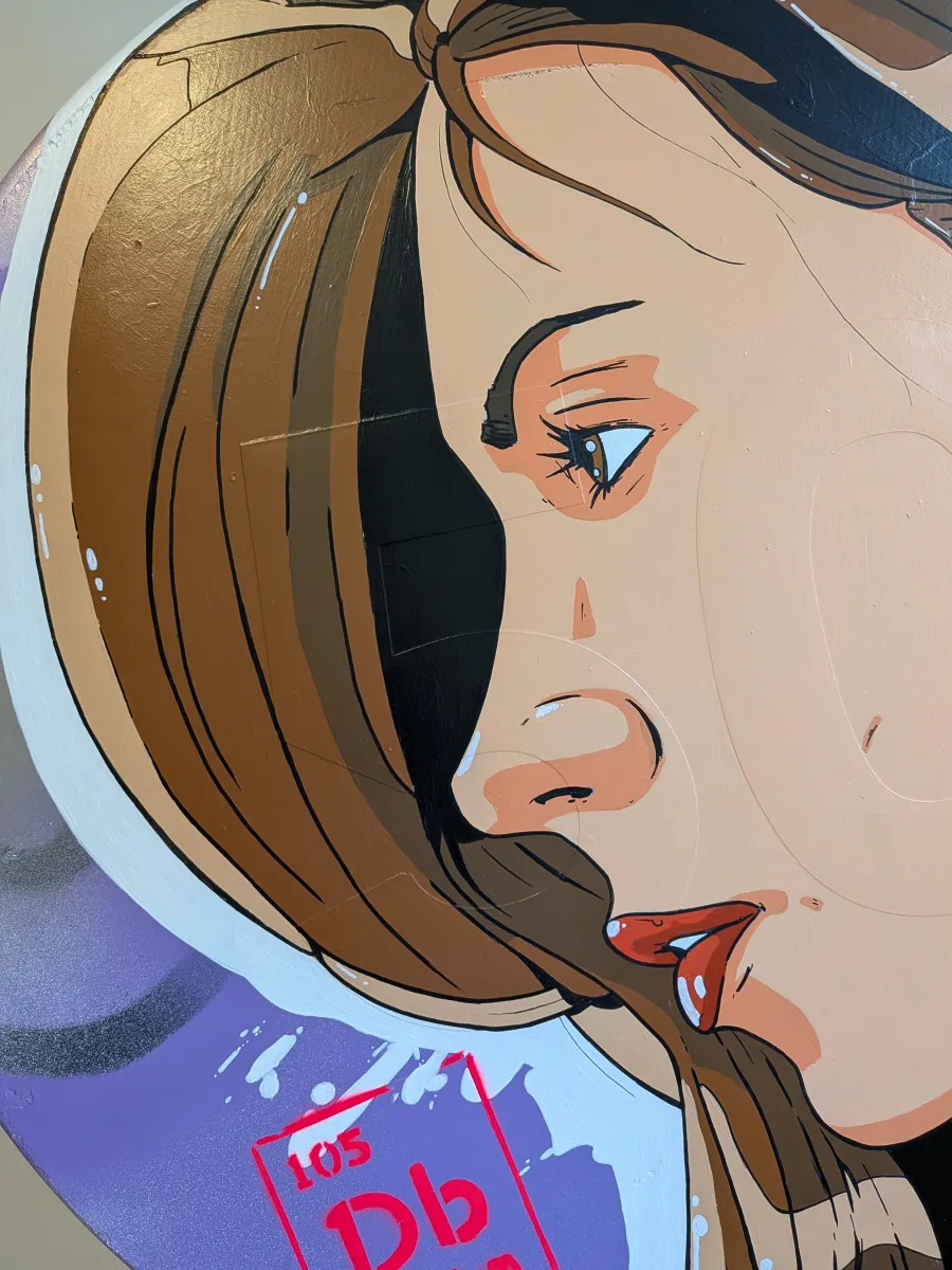 Portrait pop-art audacieux en trois-quarts sur panneau rond : la pin-up brune occupe presque toute la surface, son visage en très gros plan coupe le cadre avec une composition ultra-dynamique (cheveux qui débordent en haut, menton qui frôle le bord). L’espace vide à droite est équilibré par la pastille rouge Dubnium (Db 105) en bas gauche, créant une tension visuelle parfaite. Contours noirs massifs, aplats impeccables et reflets glossy renforcent l’effet « poster géant » découpé dans le cercle. Une vraie leçon de composition pop sur support contraint. composition pop art visage coupé, pin-up gros plan panneau rond, portrait trois-quarts street art, équilibre visuel Db 105, œuvre circulaire pop dynamique 2025, tableau signalétique composition audacieuse