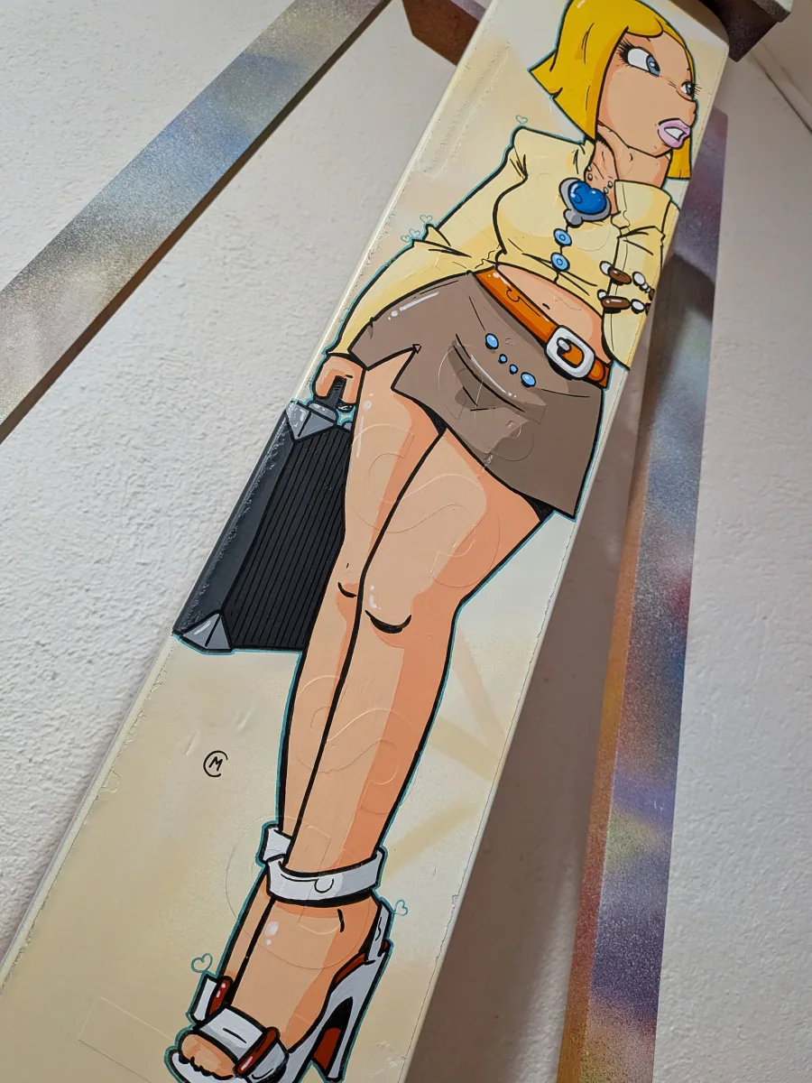 Vue en contre plongée du panneau peint avec le personnage de Circé Love habillée en business woman. Elle porte une jupe fendue, des talons hauts une ceinture orange et un chemisier court.