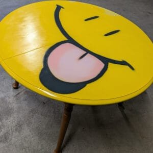 Émoji peint à la bombe de peinture sur le plateau d'une table en bois.