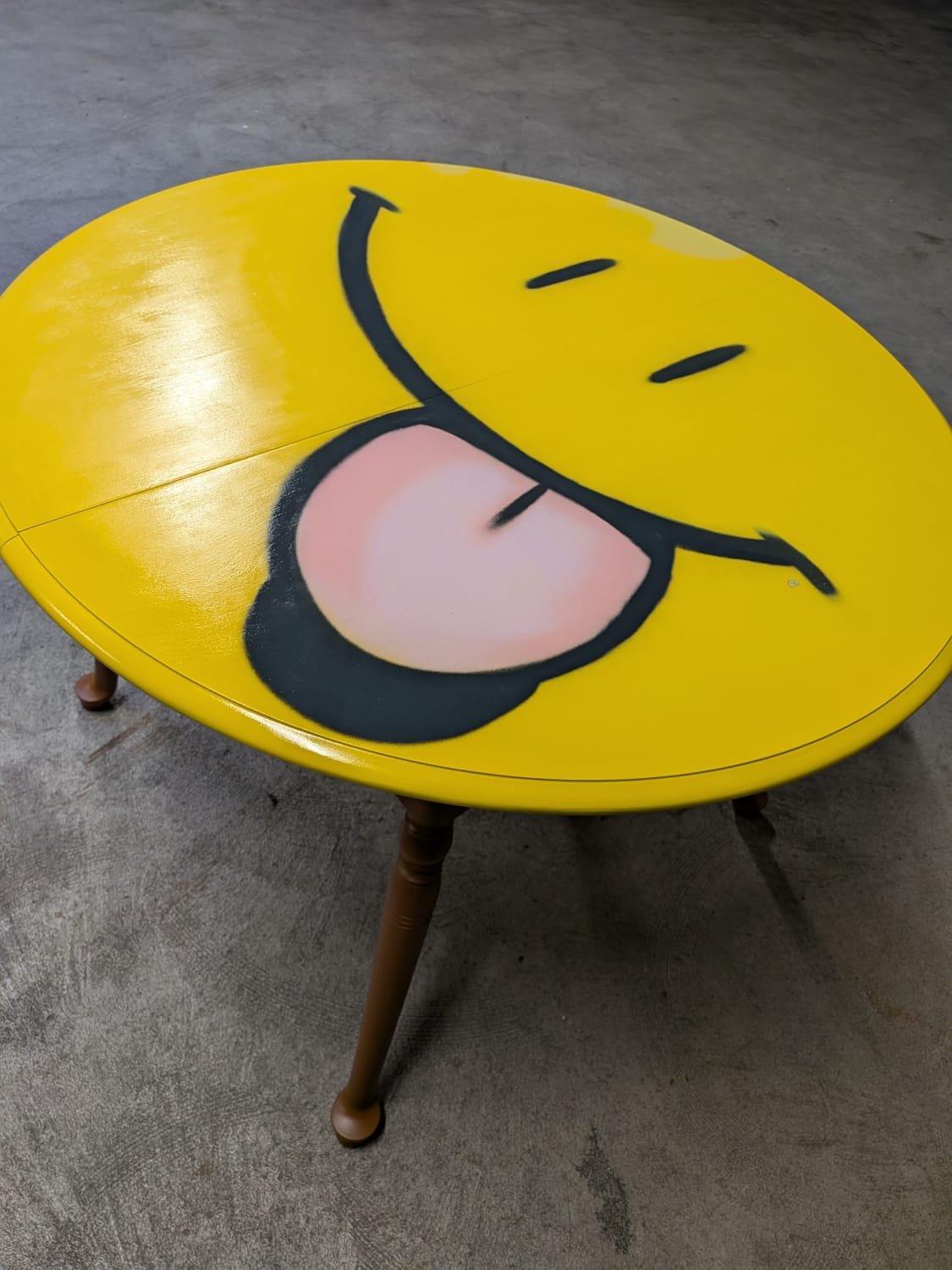 Émoji peint à la bombe de peinture sur le plateau d'une table en bois.